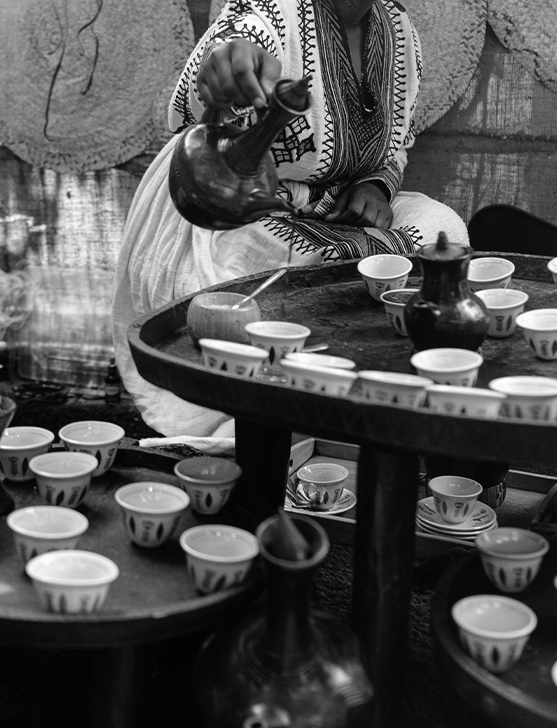 A stunning, atmospheric photo from the 2022 event showing a beautifully arranged coffee ceremony in progress with steam rising from the jebena